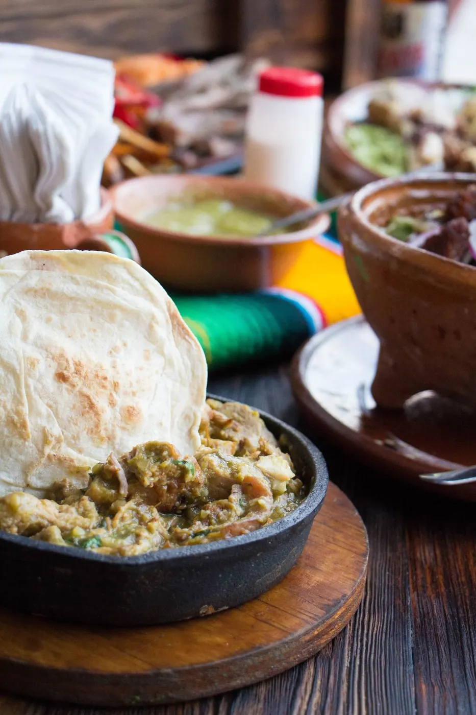 Chicharrón en salsa verde servido en sartén de hierro con tortilla de harina