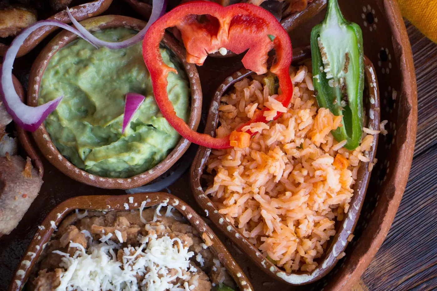 Guacamole, arroz rojo y frijoles refritos en cazuelas de barro